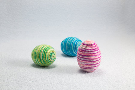 Easter eggs wrapped woolen string on a white wool background, decoration for Easter