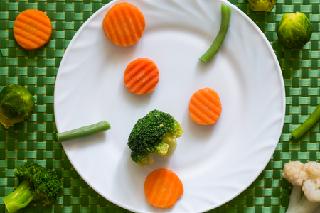 A variety of mixed vegetables on a white plate and green backgroundの写真素材