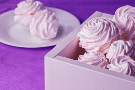 Homemade marshmallows in a box and on a plate on a purple background. Tonedの写真素材