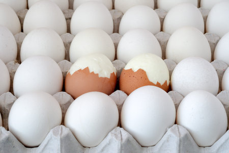 some raw and boiled eggs in tray