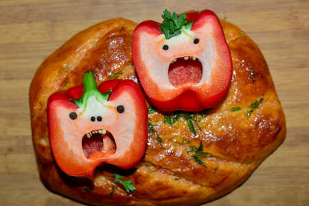 Two large red peppers, cut in half, lie on a pita bread on a cutting board, looks like a face.の写真素材