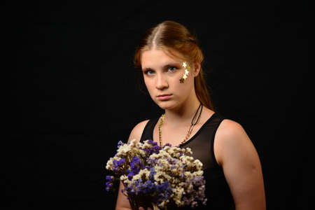 Portrait of beautiful sensual girl with wild flowers in Studio on dark background.の写真素材