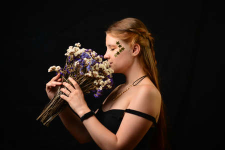 Beautiful young woman face close up portrait in studio on black. bouquet of flowers.の写真素材