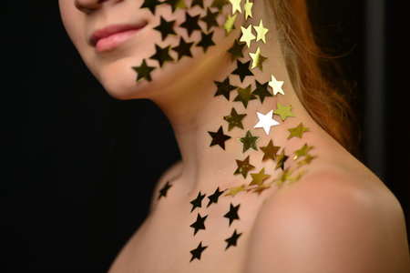 Beautiful young woman face close up portrait in studio on black. various emotions. foil stars glued...