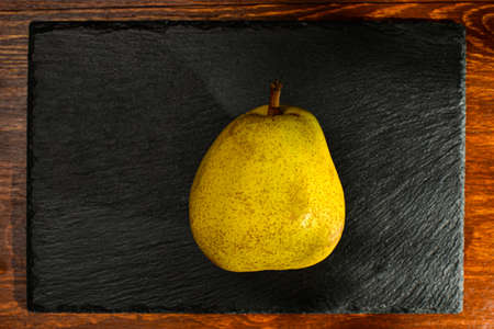 natural yellow pear on a slate board, close-up, on a wooden table, top viewの写真素材