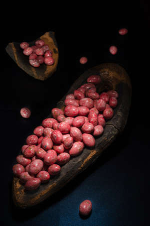 Chocolate dragees in crispy colored glaze. Dragee with almonds in a ceramic vase. Colorful candies on the tableの写真素材