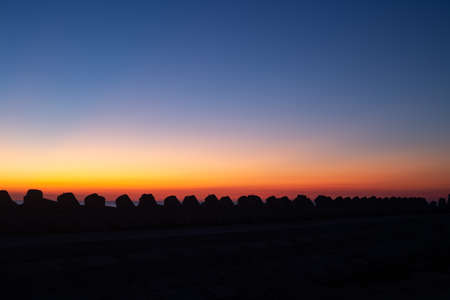 Silhouette of the sea breakwater at sunrise.の写真素材