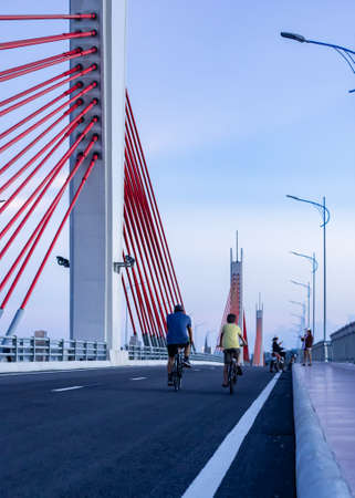 Quang Ngai City, Vietnam - September 29, 2021: Father and son ride exercise bikes in the afternoon, on a cable car bridge.  After the city ended the blockade, because of the covid 19 epidemicのeditorial素材