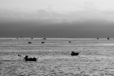 Black and white telephoto landscape photo at sea with small fishing boat and basket boat of Vietnamese fishermen. Black and white high contrast photoの写真素材