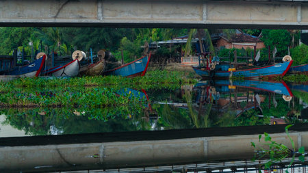 The fishing boats of Vietnamese fishermen are moored in the river, under a bridge. The river has many ducks. Icons natural landscape and boats.の写真素材