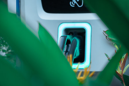 Power supply of EV charging station with cable, charging port at an electric vehicle charging station, with turquoise light. Sustainable and environmentally friendly energy conceptの写真素材