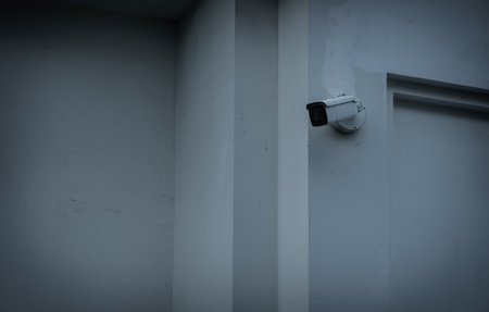 A security camera is on the white gray wall. Security surveillance concept.の写真素材