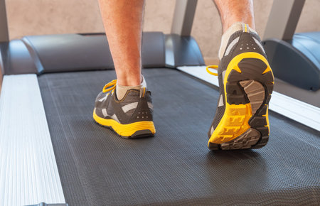 sports man in a gym on treadmill in sport shoes