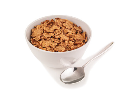 corn flakes in ceramic bowl and silver spoon on white background