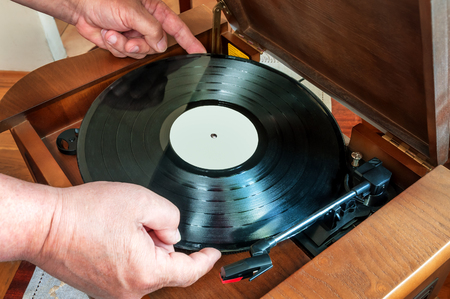 vinyl disc in hand over the retro playerの写真素材