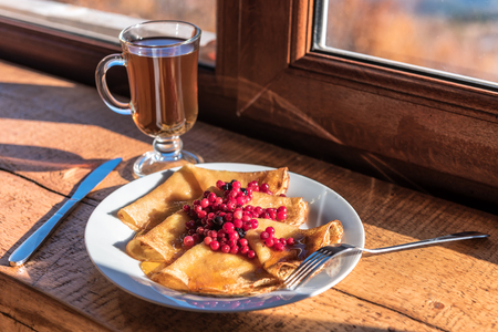 pancakes with cranberries, honey and glass of teaの写真素材
