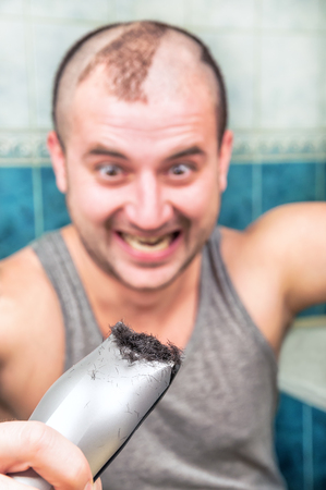 crazy man cuts himself by the hair clipperの写真素材