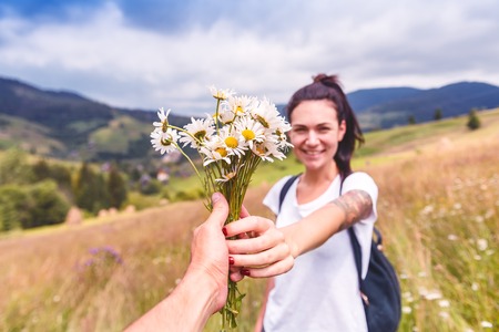 happy young girl takes the bouquet of chamomile in the mountainの写真素材