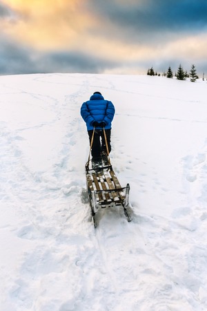 A man walking with sled up to the hill at ski resortの写真素材