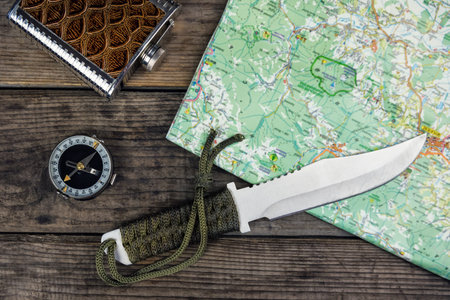 compass knife and map on wooden background