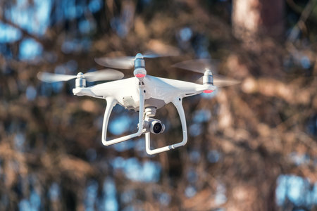 flying white quadcopter (drone) with camera