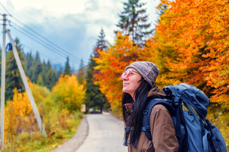girl in red glasses with backpack on the path in yellow autumn forestの写真素材