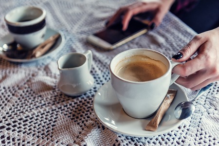 hands with cup of coffee and smartphoneの写真素材