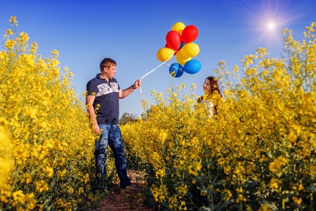 man, balloons and happy girl in blooming rape fieldの写真素材