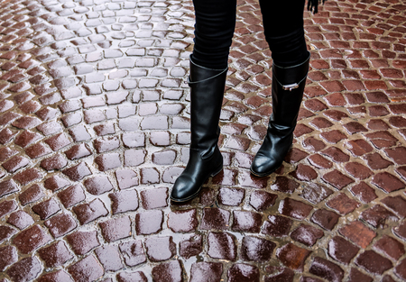 female legs in black leather boots on a wet pavementの写真素材