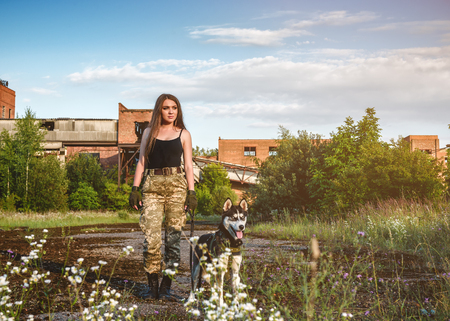 military girl walking with huskies on the ruins of abandoned buildingsの写真素材