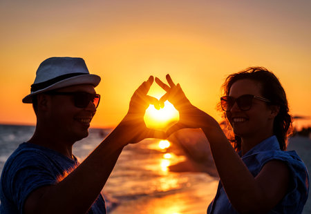 heart from hands of young happy couple on the beachの写真素材