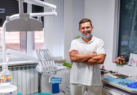 Portrait of handsome dentist in uniform at the dental officeの写真素材