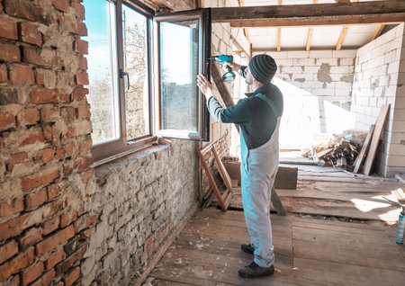 a professional window master repairs the window by electric screwdriverの写真素材