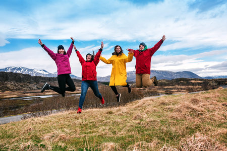 four friends jump on dry grass in Iceland