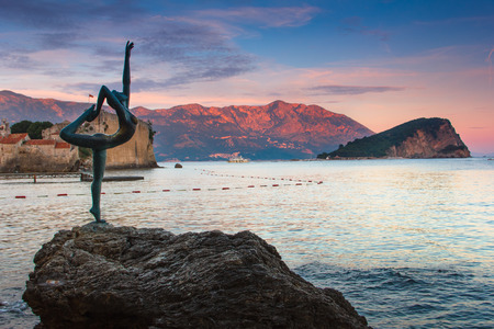 Landscape of coast: Budva old town, the Dancing Girl Statue, Sveti Nikola island and mountains at sunset. Montenegro. Adriatic sea.の写真素材