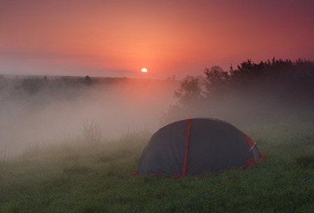 Tourist tent on green meadow at dawn. Camping background. Freedom concept.の写真素材