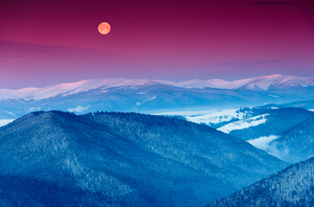 Colorful winter morning in the mountains. View of the moon and the snow-capped peaks.の写真素材