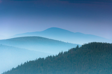 Fantastic sunrise above peaks of smoky mountain with the view into misty valley. Dramatic overcast...