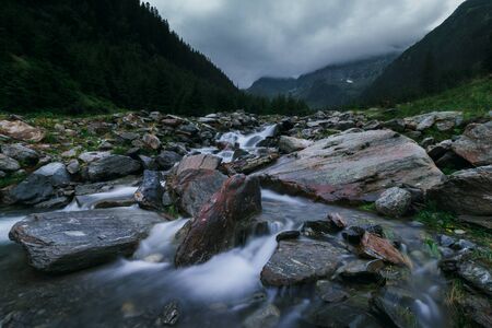 Mysterious and mystical view of the night mountains. Dramatic cloudy sky and mountain mountain river with rapids. Fagaras Mountains.Transylvania. Romania.の写真素材