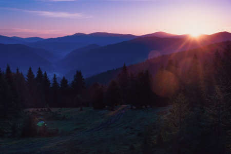 Beautiful mountain landscape at sunrise. View of hills covered forest in sunlight. Filtered image: Soft and vintage effect.の写真素材