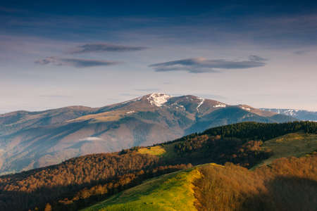 Beautiful mountains landscape in spring. Springtime in mountains. View of forested hills and grassy slopes illuminated with sunshine. dramatic sky. wild scenery. Europe.の写真素材