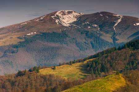 Beautiful mountains landscape in spring. Springtime in mountains. View of forested hills and grassy slopes illuminated with sunshine. dramatic sky. wild scenery. Europe.の写真素材