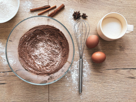 Making spicy chocolate dough. Ingredients for baking the sponge cake are laid out on a wooden table....
