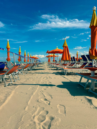 Empty sun loungers on the beach, closed umbrellas. Rows of empty beach chairs on the sand on a warm...
