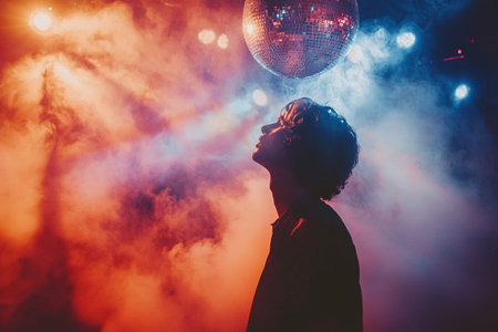 Young man indoors with stage smoke and disco ball. Concept of performance or night disco.の素材