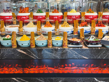 A Chinese restaurant with a food sample display. Various food items are made of plastic and look authentic. Bamboo chopsticks add realism to the food. A faux fireplace below glows with fire.の写真素材