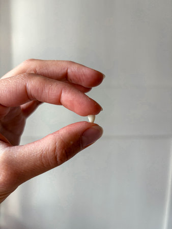 The image symbolizes the stages of childhood and adulthood. A mother holds her child's baby tooth.の写真素材
