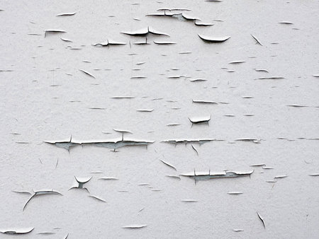 Cracks in white paint on a tin wall. Texture of cracked paint. Texture of a cracked white wall. Background and texture of a white aged wall.の写真素材