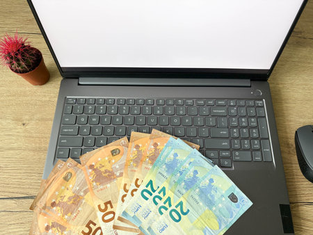 Top view of laptop with euro banknotes on keyboard in home environment. Concept of online earnings.の写真素材