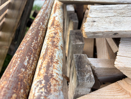 Old rusty iron pipes and wooden planks in a pile. Construction waste. Sorting of construction waste.の写真素材